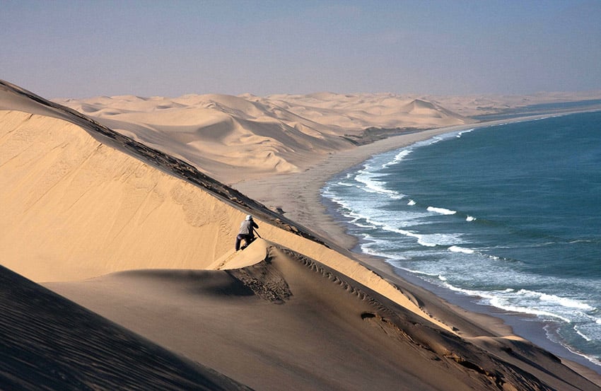 Swakopmund, photographer in sand dunes, ocean, Nambia