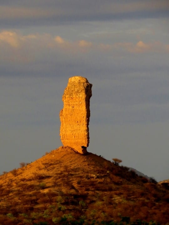 Golden evening light illuminates Vingerklip, Namibia's famous Finger of God, overlooking the Ugab Valley