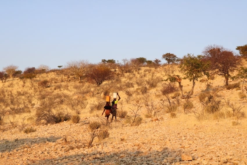 Two Himba women carrying water up a hill gracefully at Omarunga Epupa-Falls