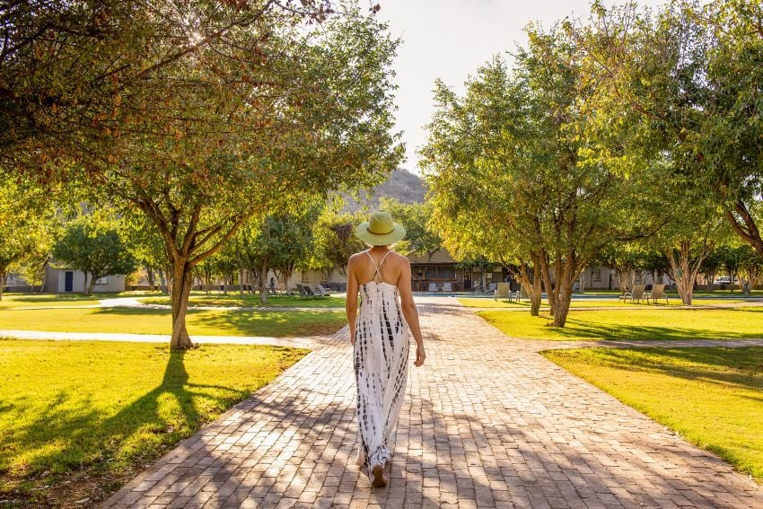 Woman walking along pathway at Damara Mopane Lodge, Namibia. 