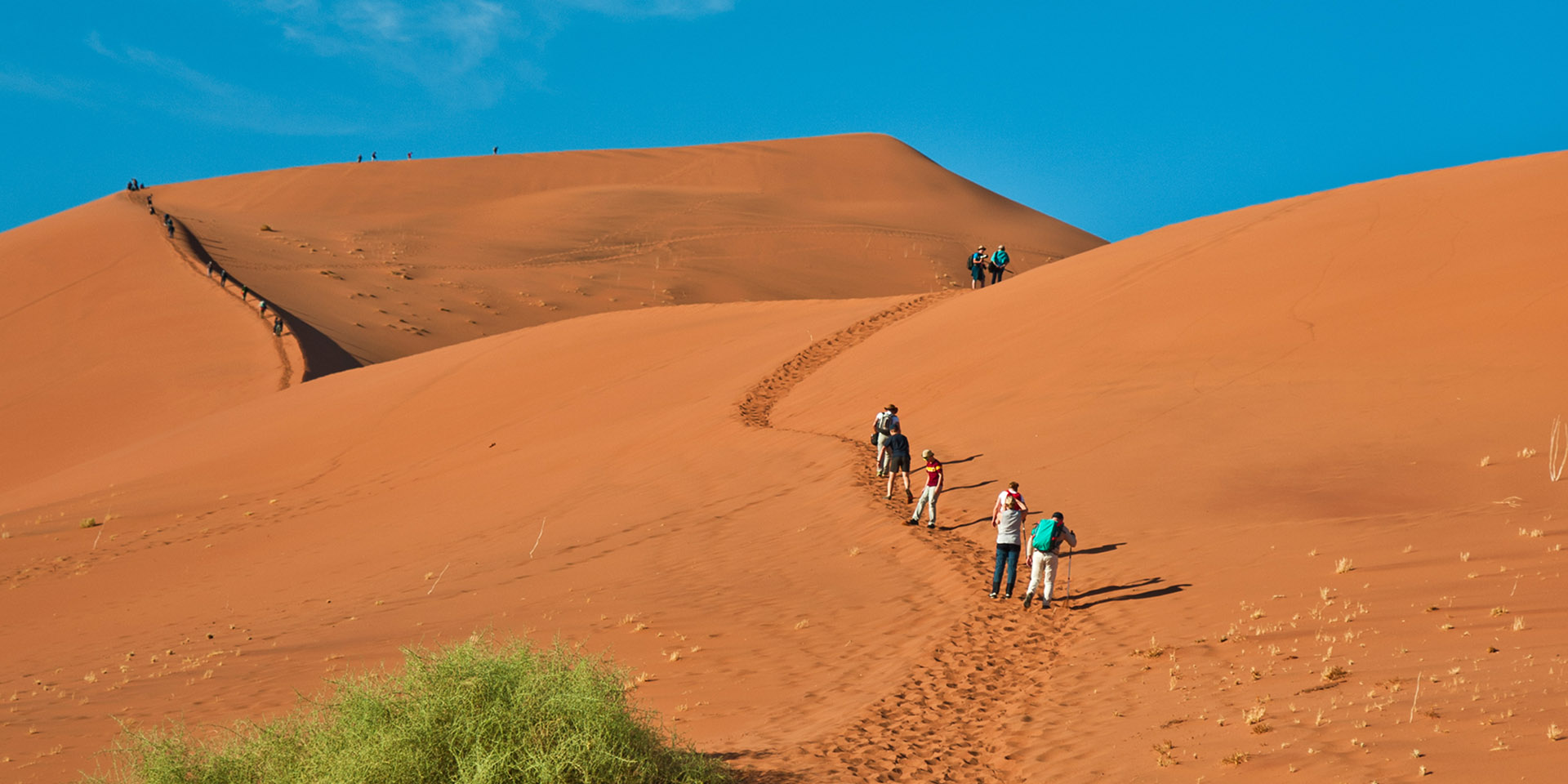 People walking up a sand dune at Sossusvlei, Namibia