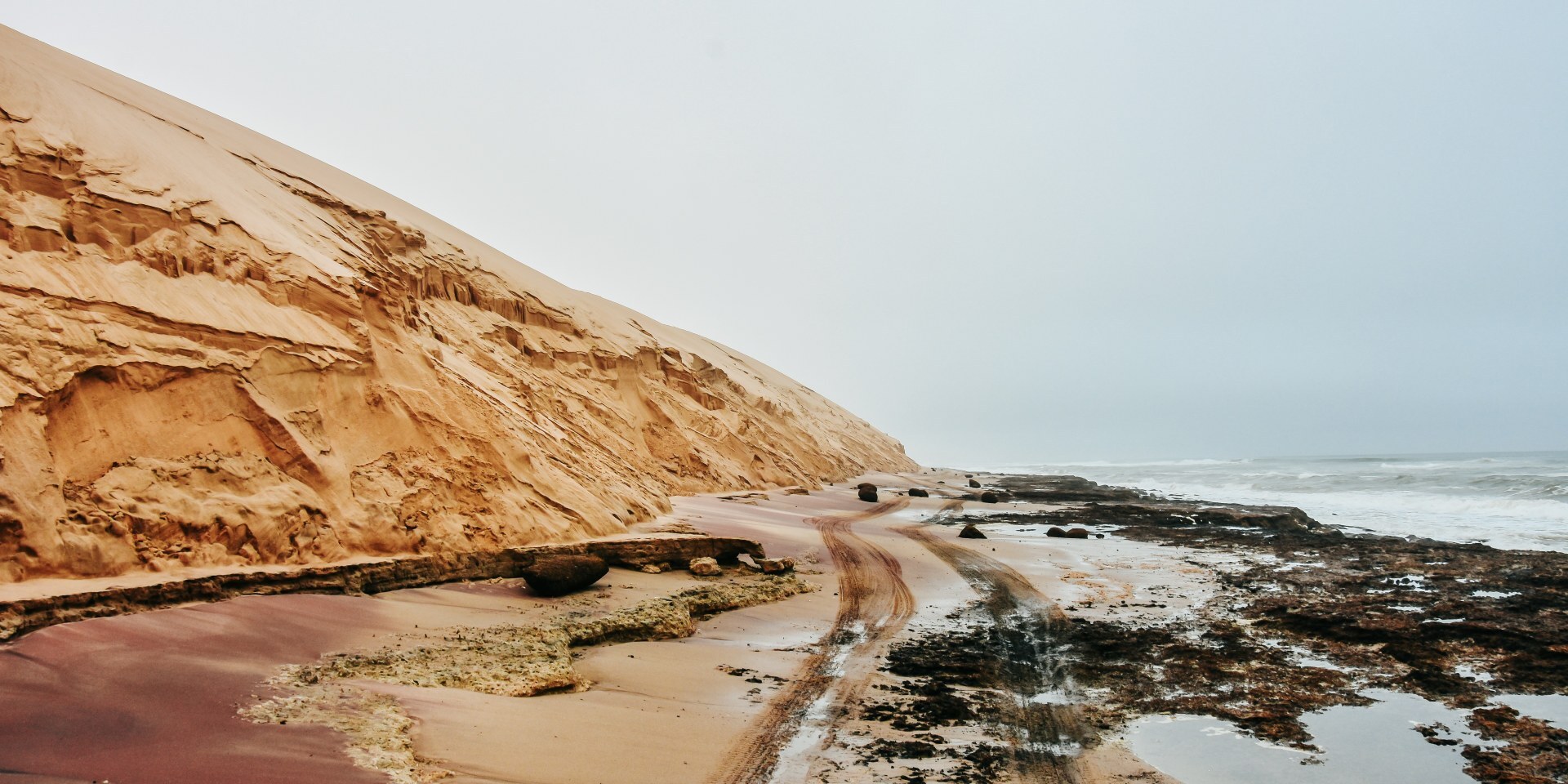 Massive sand dunes of the Namib Desert meeting the Atlantic Ocean at Sandwich Harbour, Namibia.
