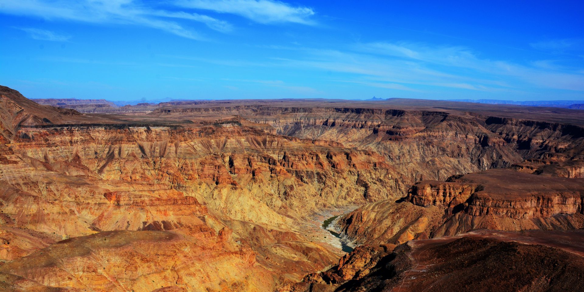Fish River Canyon in southern Namibia, showing vast rocky cliffs, deep canyon walls and dramatic desert landscape stretching into the distance.