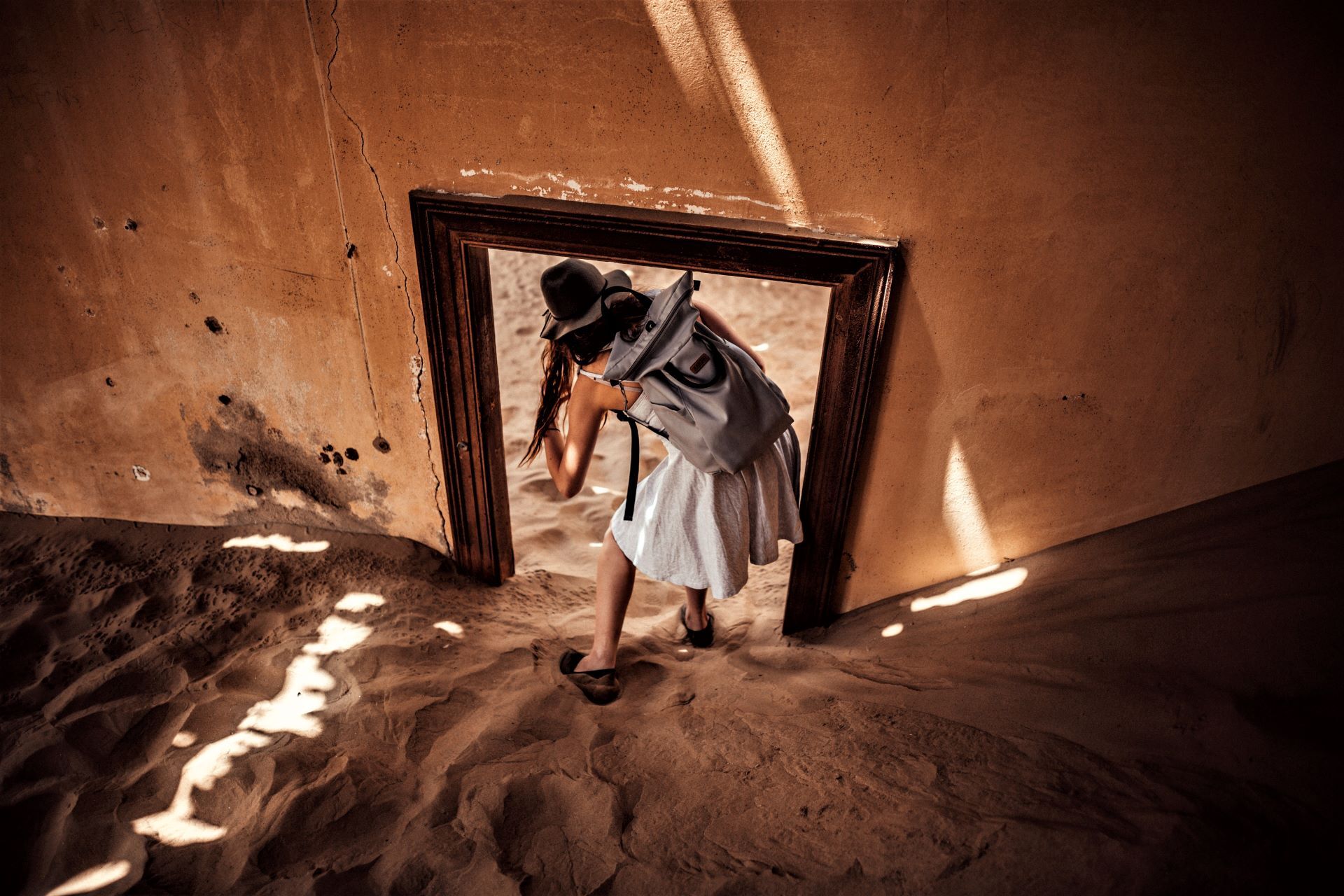 Woman going through door at Kolmanskop abandoned, sand filled homes. 