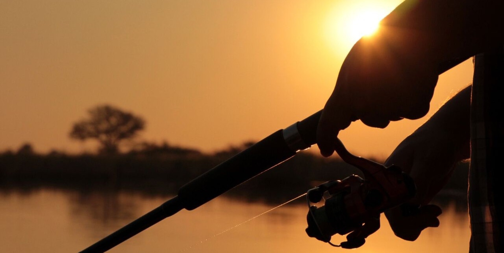 Angler casting a fishing rod into the Zambezi River in Namibia at sunset 